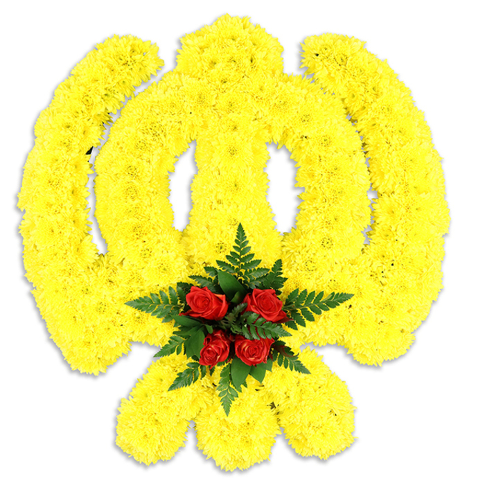An emblematic Khanda fashioned entirely from countless small, bright yellow chrysanthemum blooms dominates the frame, its sacred components-chakkar, central khanda blade and the twin kirpans-painstakingly traced in thick, consistent bands of sunny petals that read both bold and tender. The texture is plush and sculptural, the numerous flower heads tightly set so that the emblem reads as a single luminous plane with subtle undulations where light grazes the petals. Anchoring the composition, a cluster of five deep red roses sits where the circular chakkar would converge, their rich colour and velvety form forming an immediate point of reverence; these roses are enveloped by deep green fern foliage whose delicate fronds fan out to frame and heighten the contrast. The plain white background and a soft shadow beneath give the impression of a serious, freestanding tribute-a piece appropriate for a funeral procession, a gurdwara service, or a commemorative event marking Sikh heritage. The overall sensory impression is quiet and respectful: a soft floral sweetness from the chrysanthemums, the deeper rose perfume, and the clean, green note of fern leaves. As an arrangement that would sit well in community spaces around Hatch End-visible from the High Street or placed near the entrance to a local hall-it exemplifies considered craftsmanship, cultural sensitivity, and the calm dignity of flowers chosen for remembrance and honour.