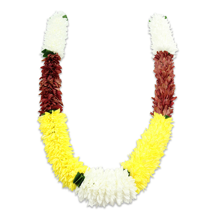 A meticulously assembled U-shaped mala sits against a pure white field, the lighting chosen to show both texture and form: a soft shadow beneath reveals the garland's gentle weight. Each arm begins with a dense, cylindrical cluster of pure white, chrysanthemum-like fabric blooms, their close-packed petals forming a fluffy, cloud-like top. These white sections transition into a concentrated band of maroon or deep reddish-brown, the darker hue adding depth and a sense of reverence. The largest, most prominent sweep is a long section of bright yellow flowers-plush, almost pom-pom-like in density-that shapes the graceful lower curve of the 'U.' At the central junction where the yellow meets, a broad, lush cluster of white petals becomes the heart of the design, visually balancing the composition. Dark green leaf-shaped accents are used sparingly as separators between colour blocks, most noticeably between the yellow and bottom white, offering a crisp, natural contrast to the fabric petals. The whole piece is clearly artificial-millions of tiny fabric petals expertly layered to replicate the fullness of traditional floral garlands-yet it retains the ceremonial dignity of a handcrafted offering used in Hindu pooja, temple rites, Indian weddings, and festivals such as Diwali or Holi. Imagining it in place, a local family might bring this garland from a Hatch End florist to decorate a doorway on Station Road or to place respectfully at a small home shrine near Headstone Lane. The visual story is one of devotion, celebration, and the quiet skill of floral artisanship.