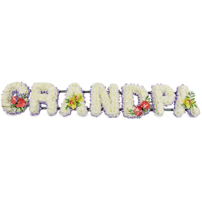 The image shows a beautifully crafted funeral flower tribute spelling out GRANDPA in bold, block capitals, displayed in a straight line on a neutral white background so each letter stands out clearly. Every letter is created from a mass of dainty, white chrysanthemum blooms set closely together, forming a dense, plush surface that feels almost like a soft, floral tapestry. The white petals, slightly curled at the tips, create gentle shadows and depth, evoking a sense of calm and purity that suits a farewell ceremony. Around the base of each letter, a narrow band of pale lavender ribbon creates a subtle border, the cool lilac tones offering just enough contrast to give the word definition without disturbing the peaceful mood. The letters sit on a dark green metal or wooden frame, practical and sturdy, the kind of construction an experienced local florist near Hatch End station would use to ensure the tribute travels safely to a church or crematorium along Uxbridge Road. Carefully placed accent sprays introduce colour and meaning: on the 'G' and the 'D', dramatic red anthuriums with their smooth, waxy, heart-shaped petals and bright yellow centres nestle into lush green foliage, with tiny notes of purple filler flowers that echo the lavender trim. On the first 'A' and the final 'A', clusters of soft yellow-green orchids arc gracefully across the white base, their intricate throats and slightly translucent petals catching the light and suggesting resilience and enduring love. Together, these elements form a touching memorial design, the type of personalised tribute families in Hatch End might choose to honour a much-loved grandfather at a funeral service, wake, or graveside gathering, when words alone do not feel enough.