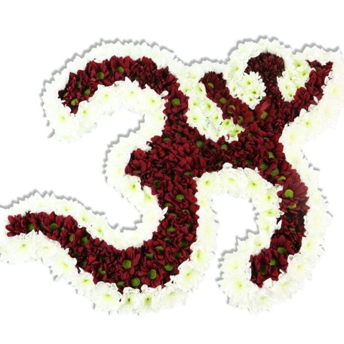 Against an unadorned white backdrop, this sculptural floral Om (Aum) symbol commands attention through its meticulous texture and reverent form. The primary mass of the character - the distinctive '3'-shaped loop, the descending S-like stroke, and the small crescent with its dot above - is tightly composed of rich maroon and deep-burgundy chrysanthemum-style blooms. Each tiny pompon reveals a small lime-green centre, like an echo of new life tucked into the dark petals, creating subtle tonal variation across the body of the sign. Framing and defining the symbol is a thick, flowing border of pristine white spray chrysanthemums whose fine, delicate petals carve clean negative spaces and heighten the icon's clarity. The flowers are so densely arranged that the surface appears both plush and architected, and a delicate shadow beneath confirms its three-dimensional presence on the white field. The lighting is soft and even, lending the reds a warm depth and the whites a cool lucency; the arrangement's tactile quality - cool to the touch, layered petals yielding under fingertips - evokes quiet consolation. This piece reads as a ceremonial object, ideal for religious observances, memorial services, or as a meditative focus at yoga workshops. For those in the Hatch End area, it brings to mind the measured calm of Headstone Lane and the reflective spaces near Headstone Manor and Museum - a neighbourly tribute fashioned with the skill and care of a seasoned florist familiar with local customs and the need for meaningful, dignified floral art.